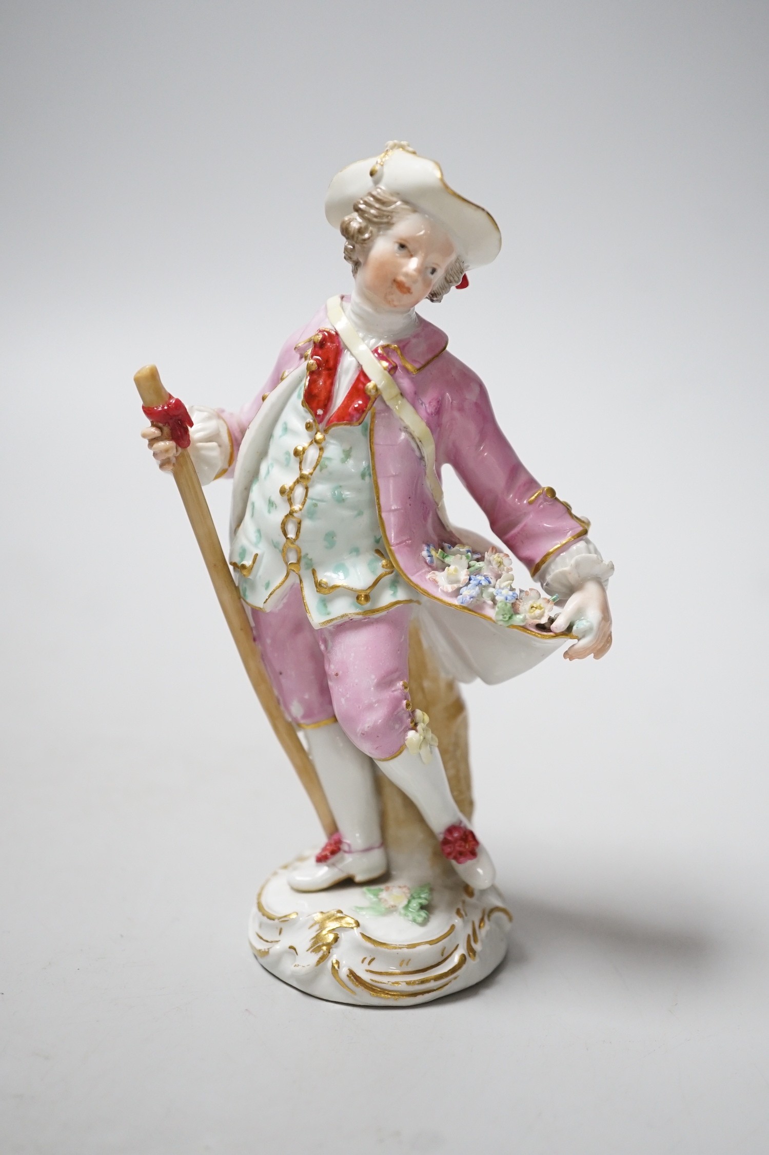 A Meissen figure of a young man with walking stick and his tail full of flowers, late 18th century, blue crossed swords to back of base